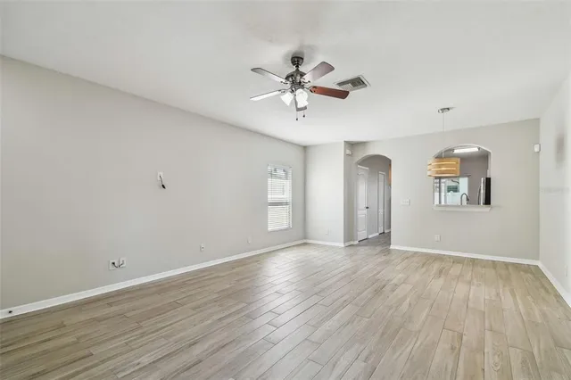 an empty room with wooden floor exposed radiator and windows
