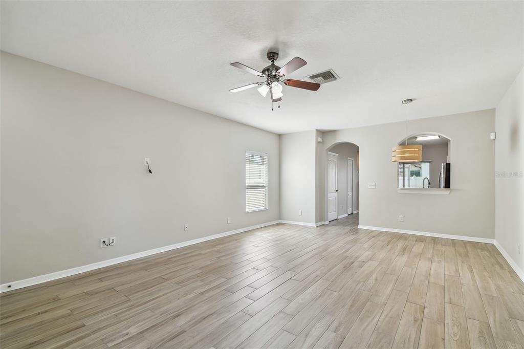 16227 Swan View Circle Odessa, FL 33556 - Photo 4 of 29 an empty room with wooden floor chandelier fan and windows