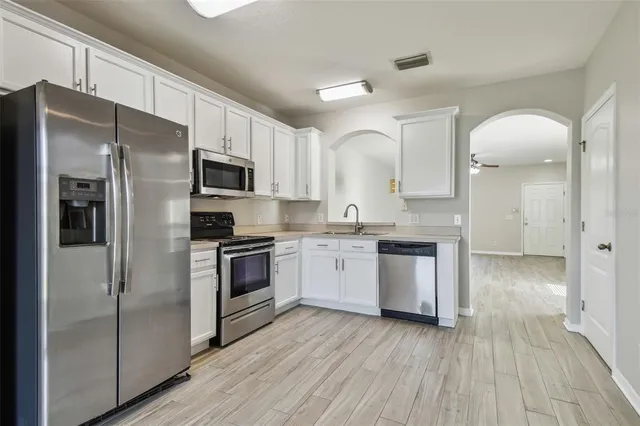 a kitchen with stainless steel appliances granite countertop grey cabinets a stove a sink and dishwasher