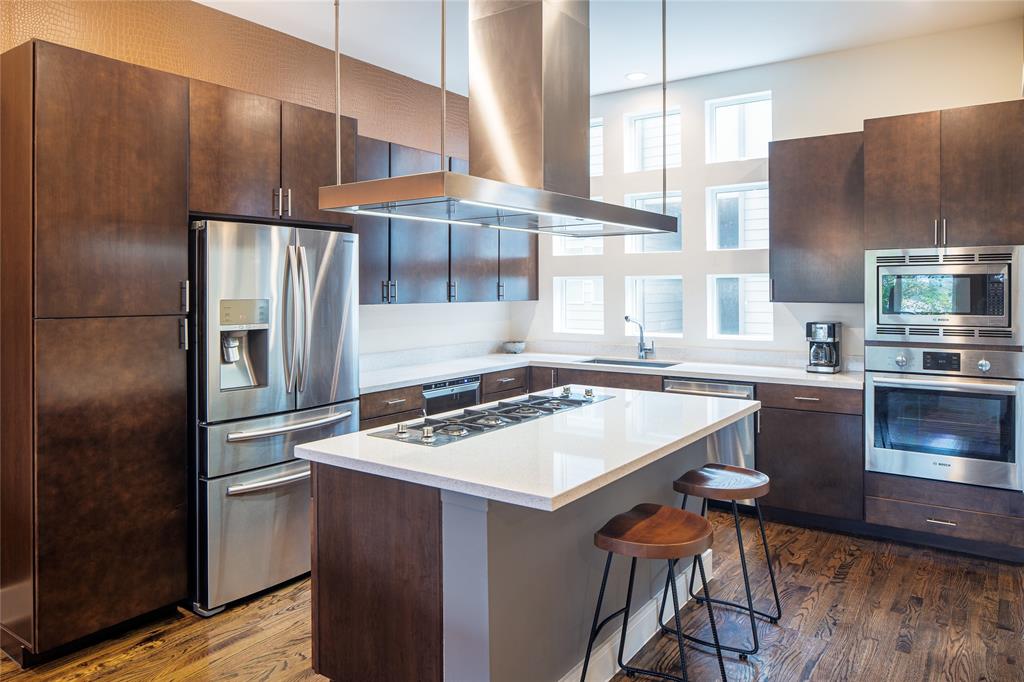 4610 Steel Street Dallas, TX 75219 - Photo 7 of 10 a kitchen with stainless steel appliances a refrigerator a sink a stove and white cabinets with wooden floor