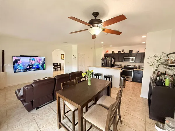 a living room with furniture kitchen view and a chandelier