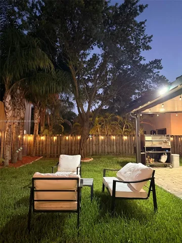 a view of a backyard with table and chairs potted plants and large tree