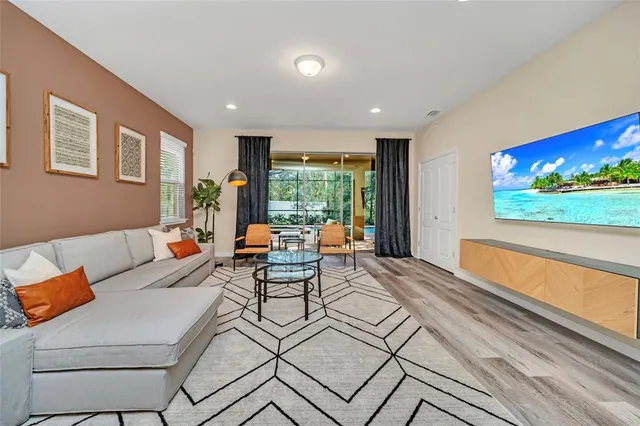 a living room with furniture a flat screen tv and a floor to ceiling window