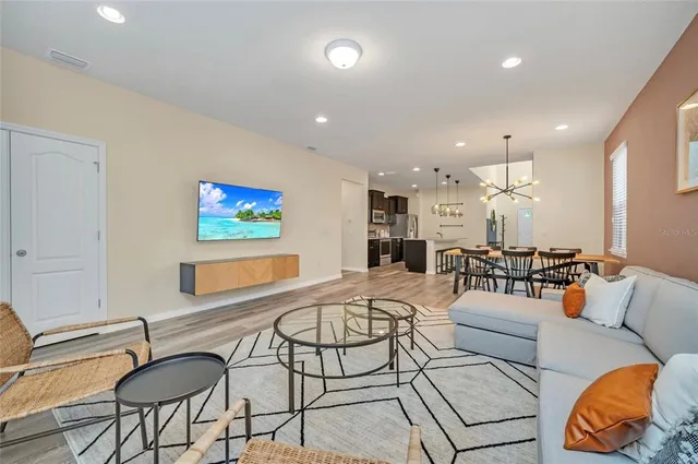 a living room with furniture kitchen view and a large window