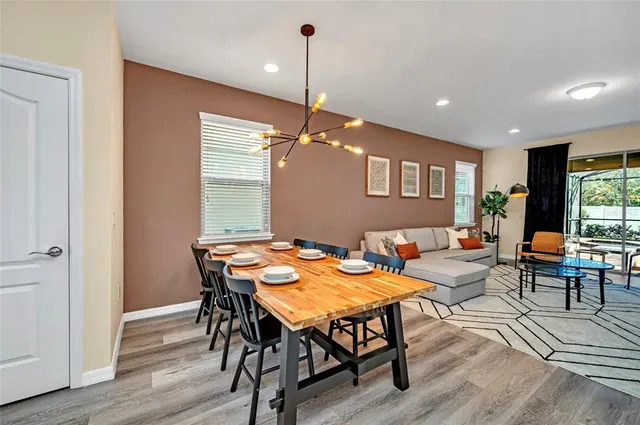 a dining room with wooden floor a chandelier a wooden table and chairs