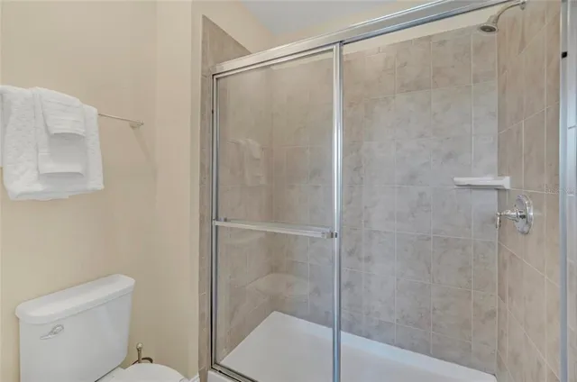 a bedroom with a bed a chair and potted plant on the dresser