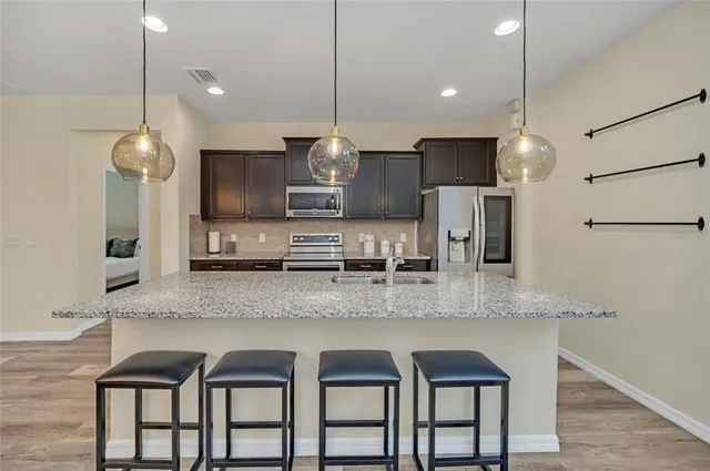 a large kitchen with granite countertop a sink a counter space appliances and cabinets