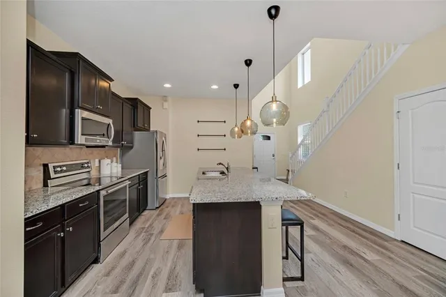 a kitchen with stainless steel appliances granite countertop a sink a stove and a wooden floors