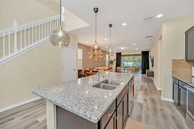 a kitchen with granite countertop a table chairs and a wooden floor