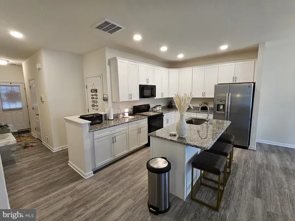 a kitchen with stainless steel appliances granite countertop a stove a sink a microwave a refrigerator and white cabinets