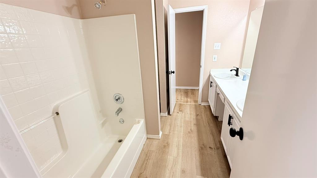 12259 Rim Rock Road Dallas, TX 75253 - Photo 15 of 17 Bathroom featuring double vanity, light wood-style flooring, and washtub / shower combination