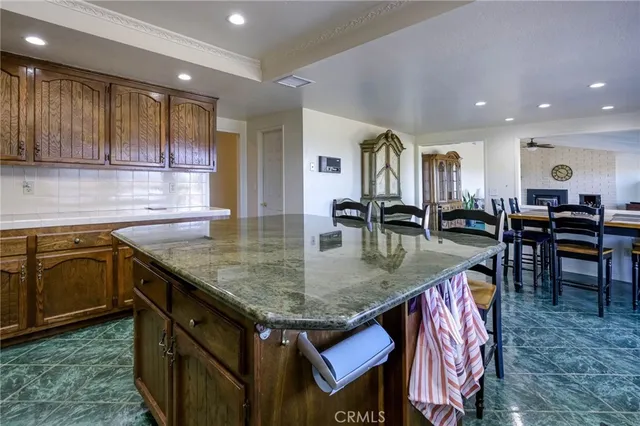 an open kitchen with granite countertop a table chairs sink and cabinets