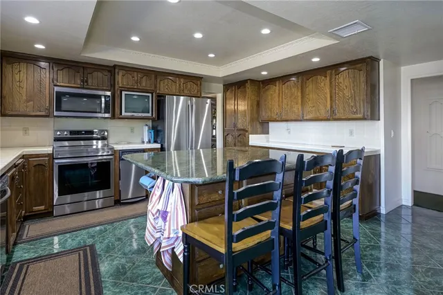 a kitchen with stainless steel appliances kitchen island granite countertop a table chairs sink and stove top oven