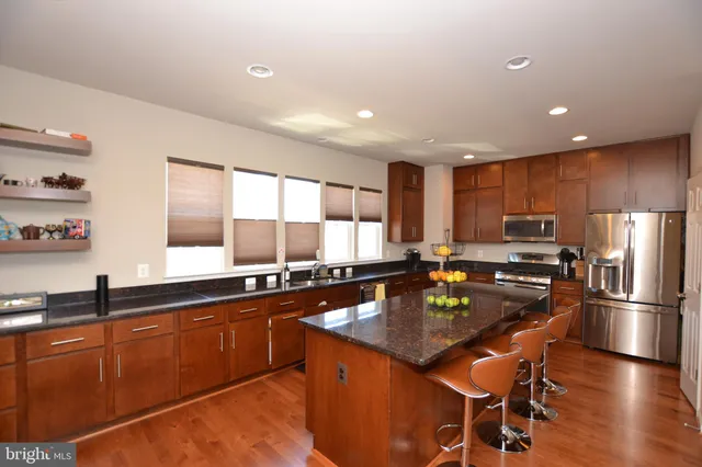 a kitchen with stainless steel appliances granite countertop a sink a stove and refrigerator