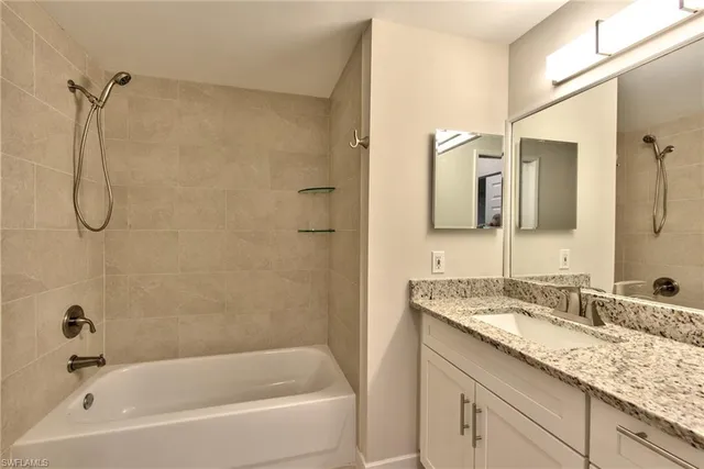 a bathroom with a granite countertop sink a mirror and a bathtub