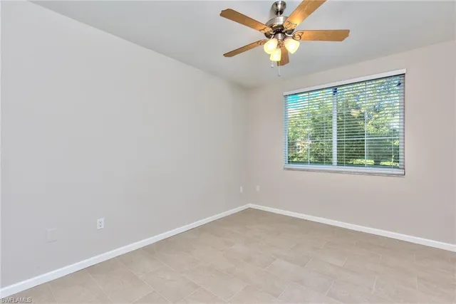 an empty room with a window and a fan