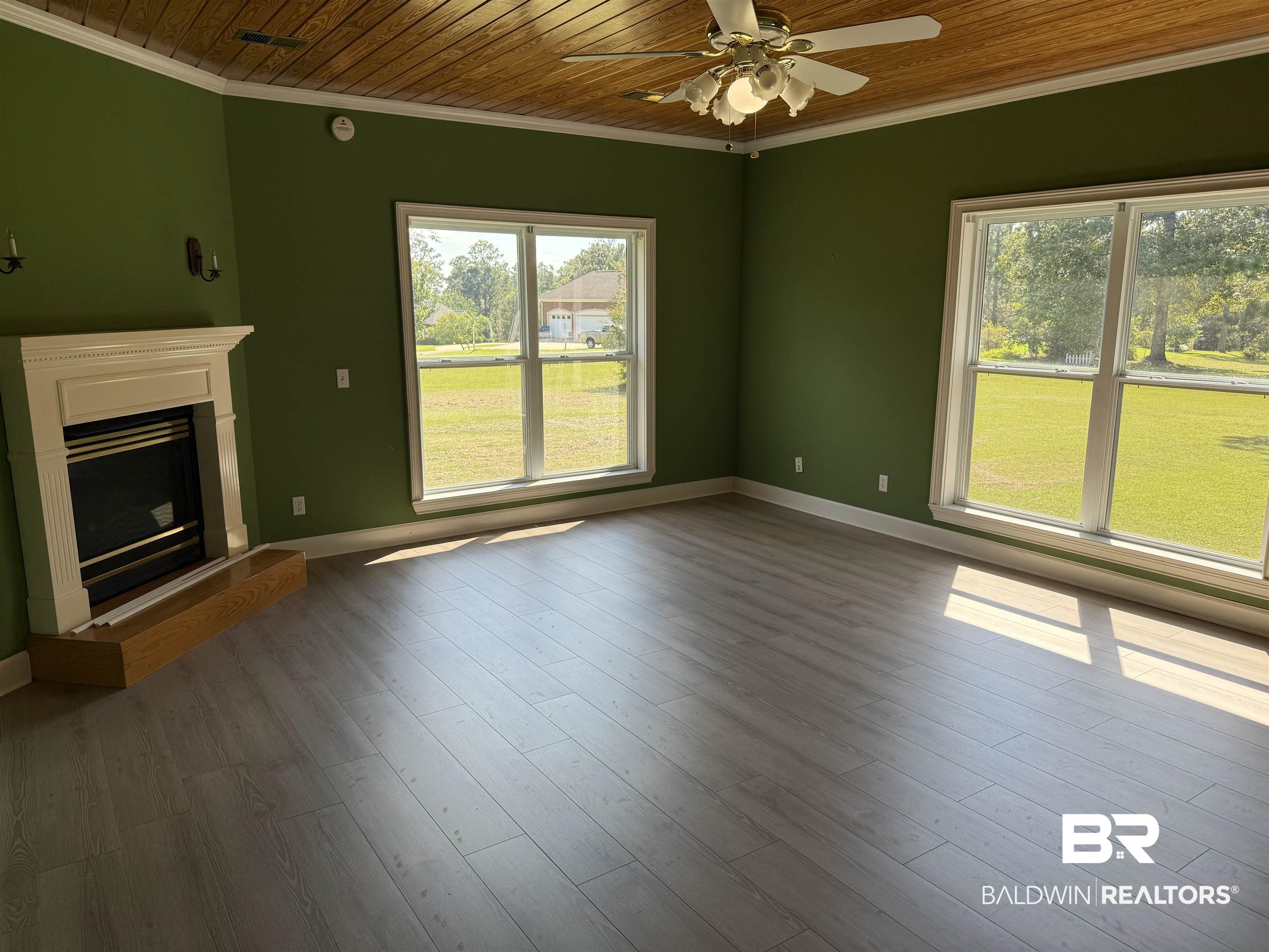 415 Juniper Creek Road Brewton, AL 36426 - Photo 20 of 35 Unfurnished living room featuring crown molding, wood ceiling, plenty of natural light, a fireplace with raised hearth, and dark wood-type flooring