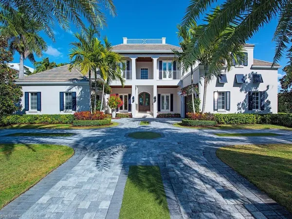 a front view of a house with swimming pool and large trees