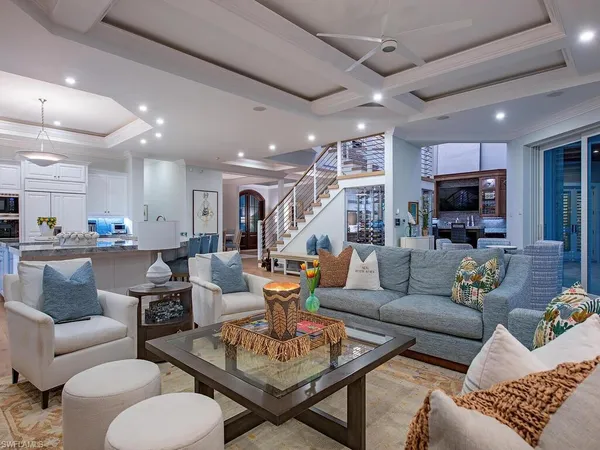 a living room with furniture kitchen view and a wooden floor