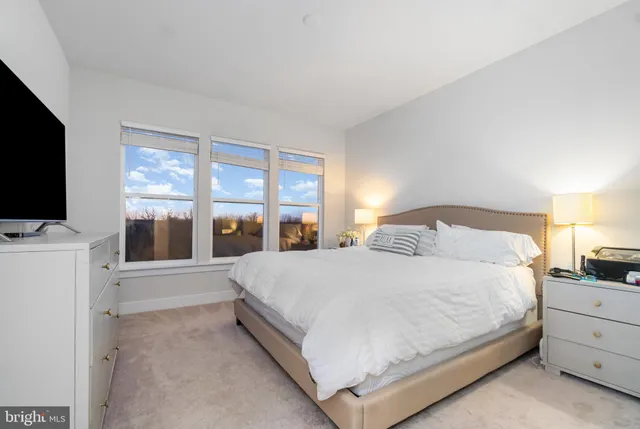 a bedroom with a large bed and a flat tv screen on dresser