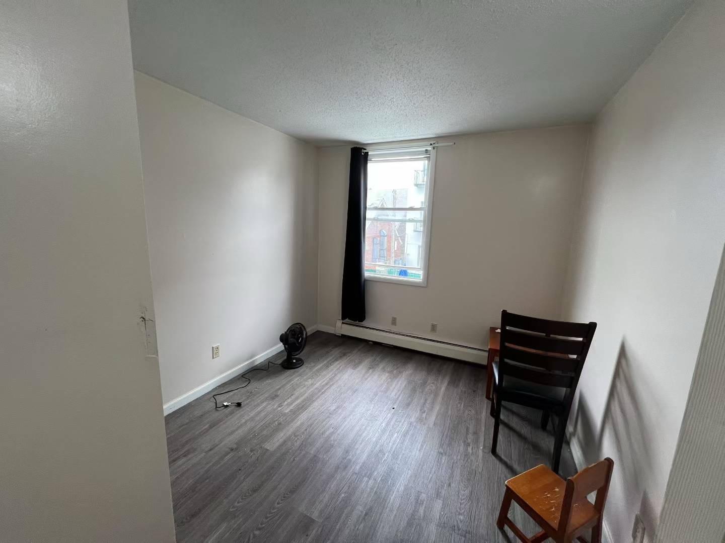 34-18 103rd Street Queens, NY 11368 - Photo 5 of 12 a view of an empty room with wooden floor and a window