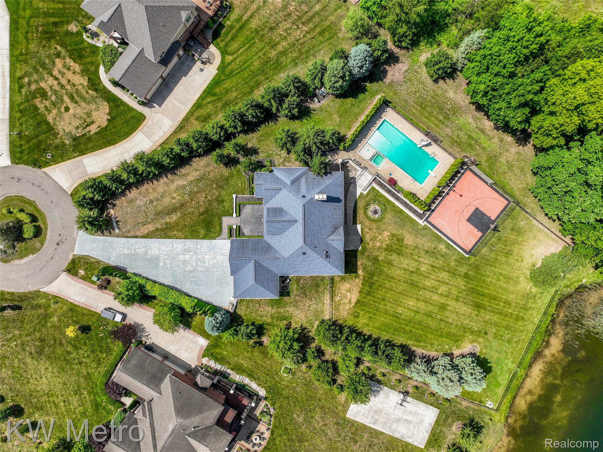 65884 Windrose Court Ray, MI 48096 - Photo 26 of 82 Expansive property featuring a private swimming pool, dedicated sports court, large paved driveway, and mature landscaping