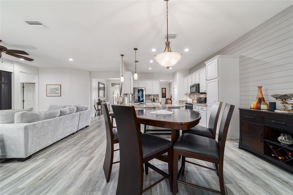 11888 Southeast 91st Circle Summerfield, FL 34491 - Photo 24 of 67 a view of a dining room and livingroom with furniture wooden floor a rug a flat screen tv a painting and a chandelier