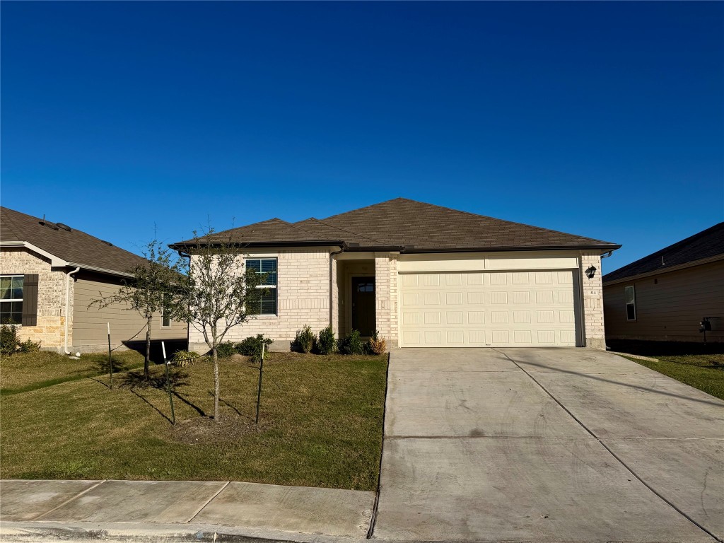 Ranch-style house with brick siding, a front lawn, driveway, a garage, and roof with shingles