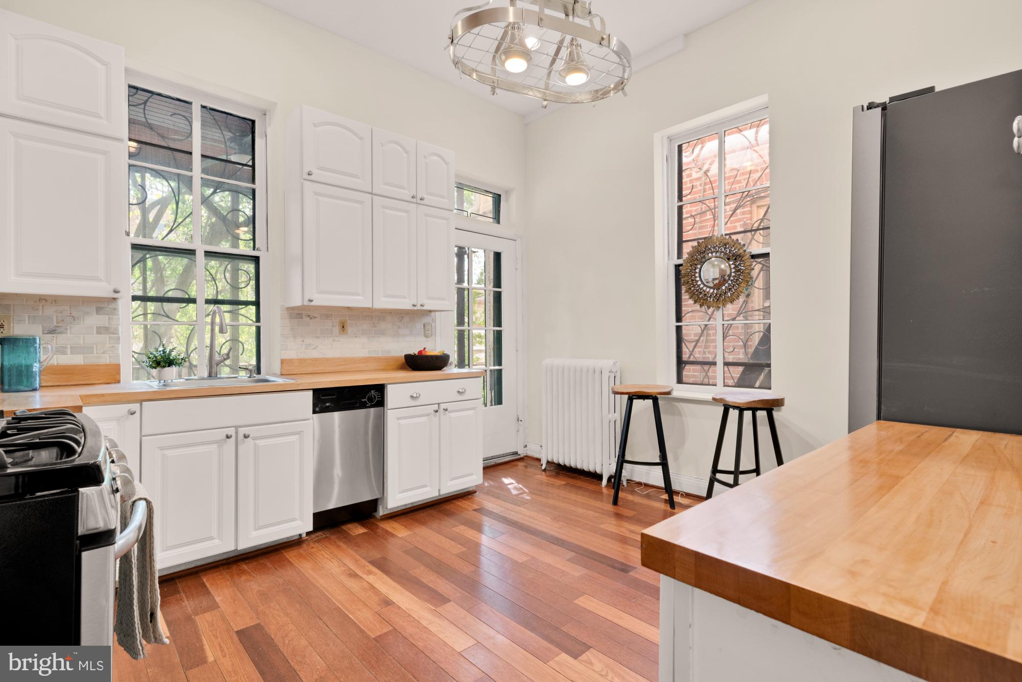 2133 Bolton Street Baltimore, MD 21217 - Photo 13 of 53 a kitchen with stainless steel appliances granite countertop a stove top oven a sink dishwasher and a refrigerator with wooden floor