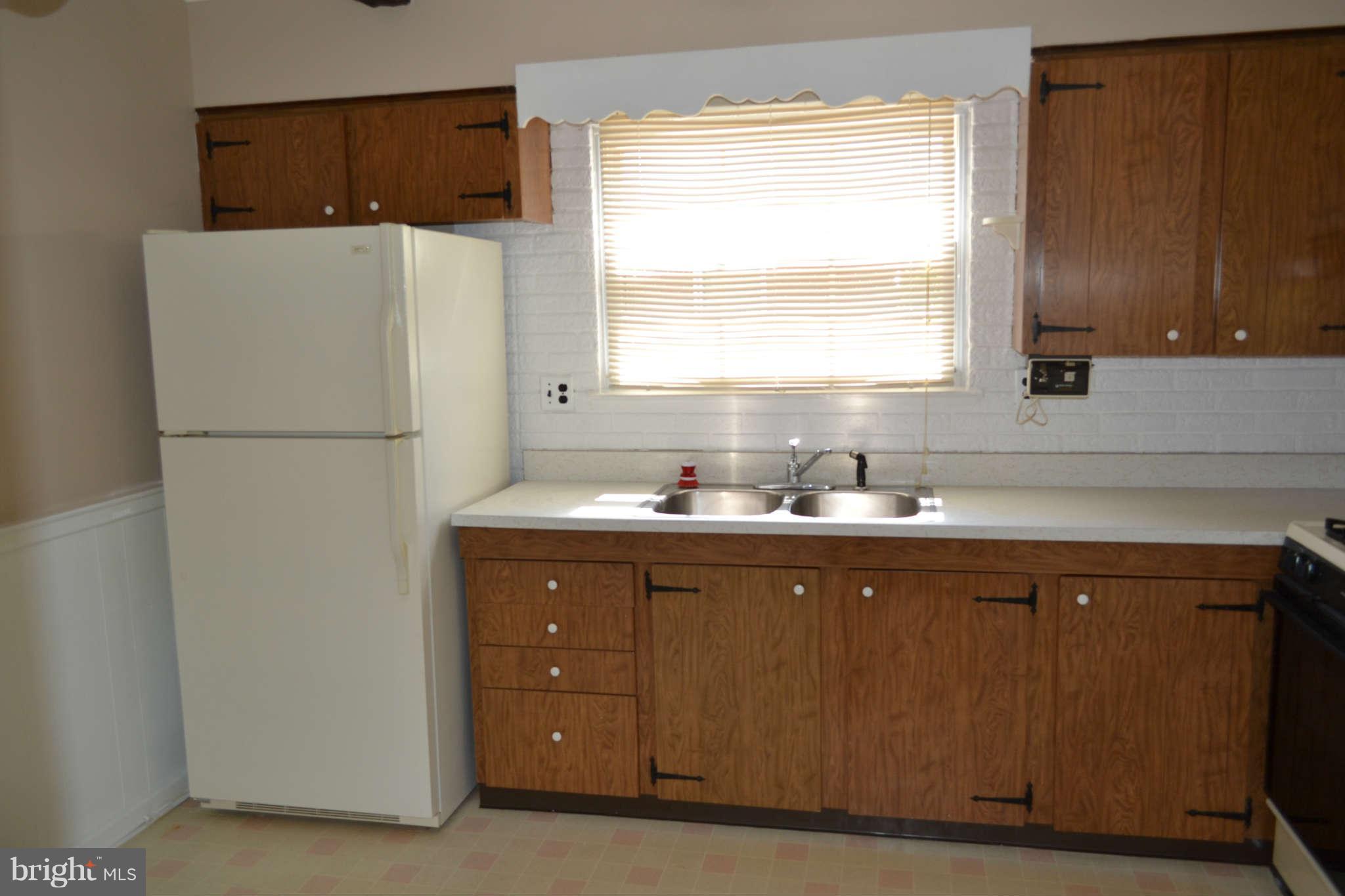 1406 Woodbridge Road Baltimore, MD 21228 - Photo 3 of 18 a kitchen with a refrigerator sink and cabinets