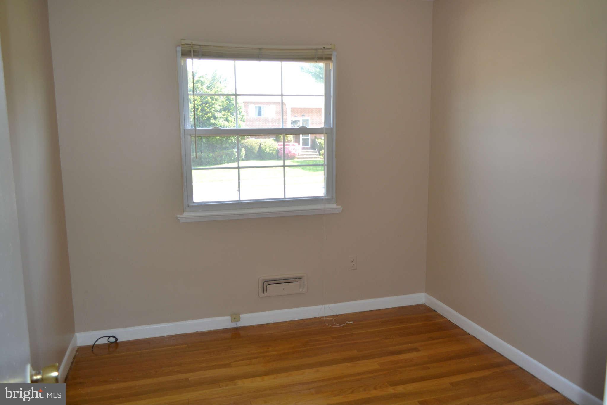1406 Woodbridge Road Baltimore, MD 21228 - Photo 10 of 18 an empty room with wooden floor and windows