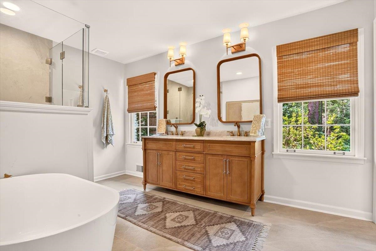 7674 Apple Valley Road Germantown, TN 38138 - Photo 10 of 15 Bathroom featuring a freestanding soaking tub, glass-enclosed shower, dual vanity with undermount sinks, and windows with natural wood blinds