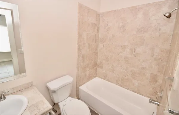 a white toilet sitting next to a white sink and vanity