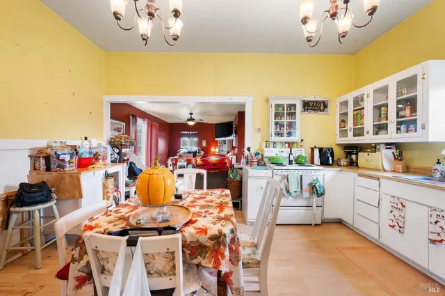 a view of a dining room with furniture a chandelier and kitchen view
