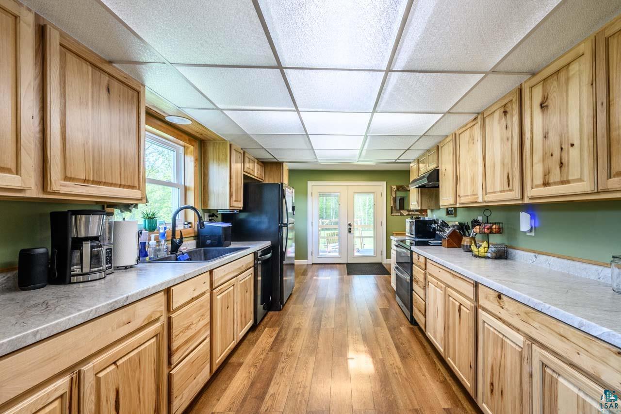 2581 O'Rourke Road Hibbing, MN 55746 - Photo 7 of 61 Galley kitchen featuring light wood cabinetry, wood-finish flooring, light-toned countertops, and French doors