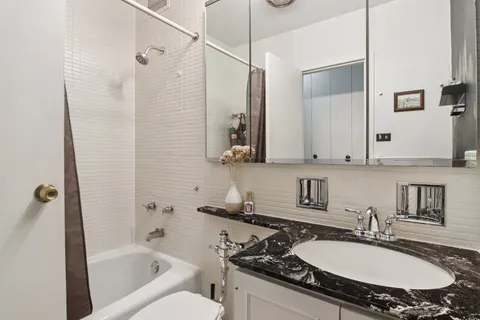 a bathroom with a granite countertop sink mirror and a bathtub