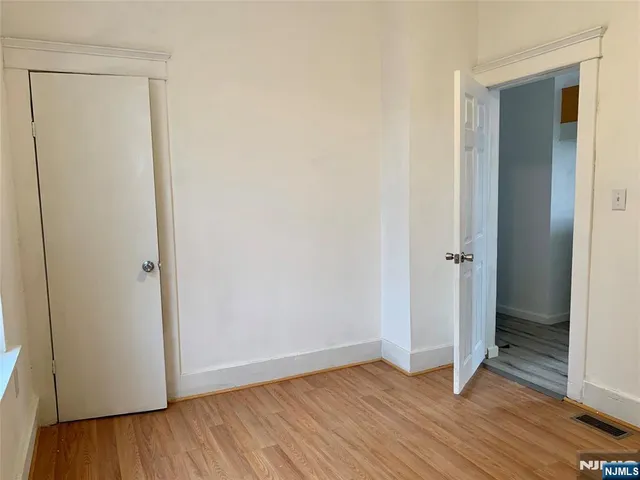 a view of an empty room with wooden floor and closet
