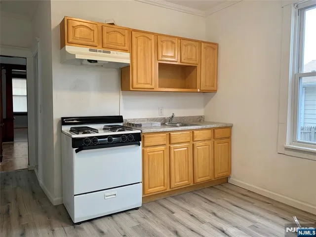a kitchen with granite countertop wooden cabinets and a stove top oven