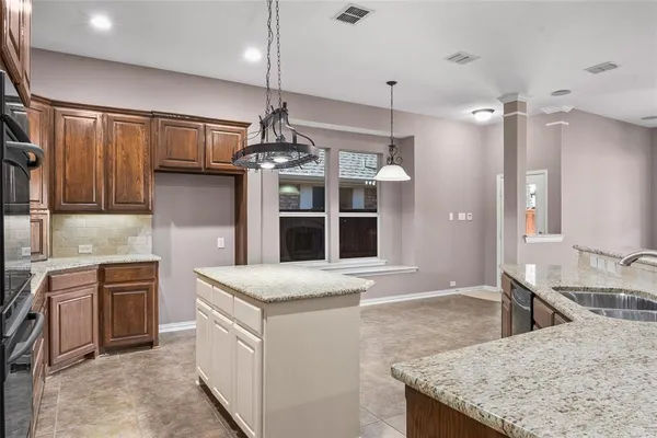 a kitchen with kitchen island granite countertop wooden cabinets and a stove top oven