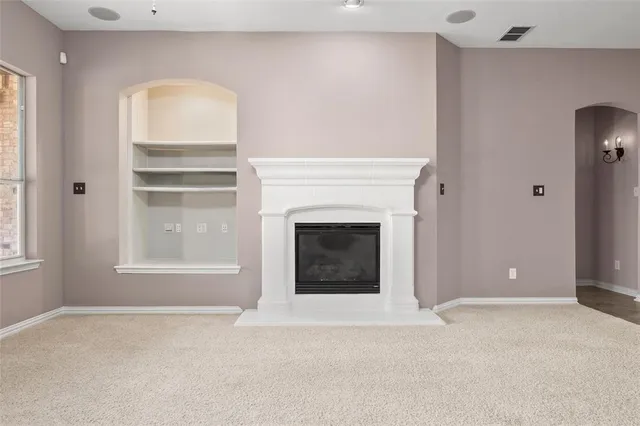 an empty room with chandelier fan and fireplace