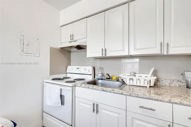 a kitchen with granite countertop white cabinets and white appliances