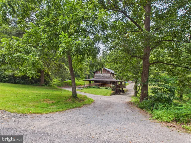 a view of a house with a big yard and large trees