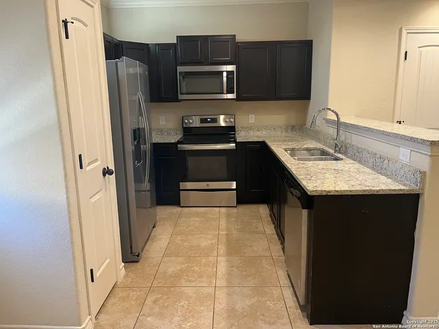 a kitchen with stainless steel appliances granite countertop a refrigerator and a stove top oven