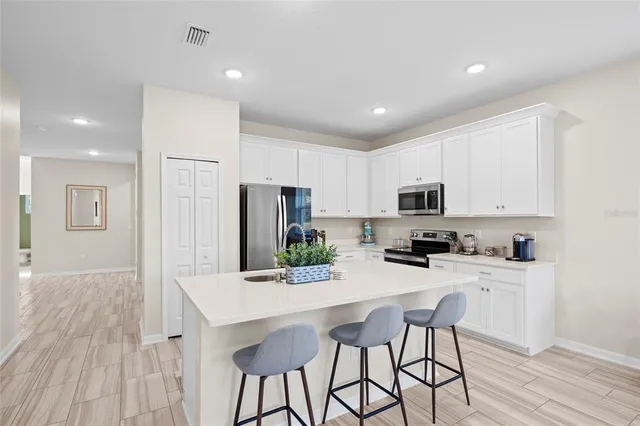 a kitchen with stainless steel appliances a microwave a stove a sink dishwasher a refrigerator with white cabinets and wooden floor