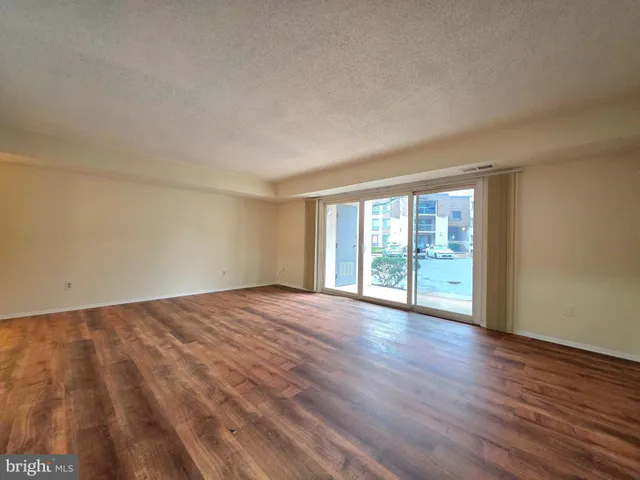 a view of empty room with wooden floor and window