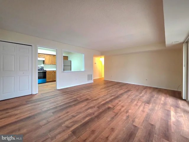 a view of a big room with wooden floor and a kitchen