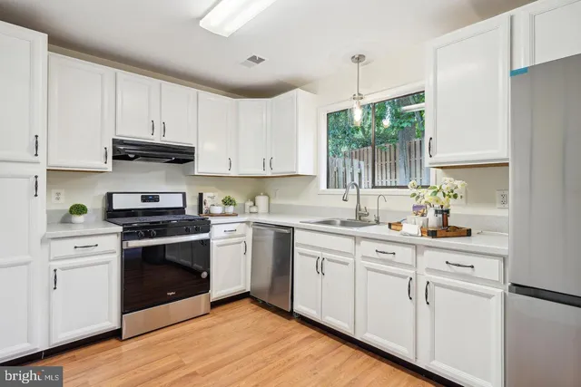 a kitchen with white cabinets sink and appliances
