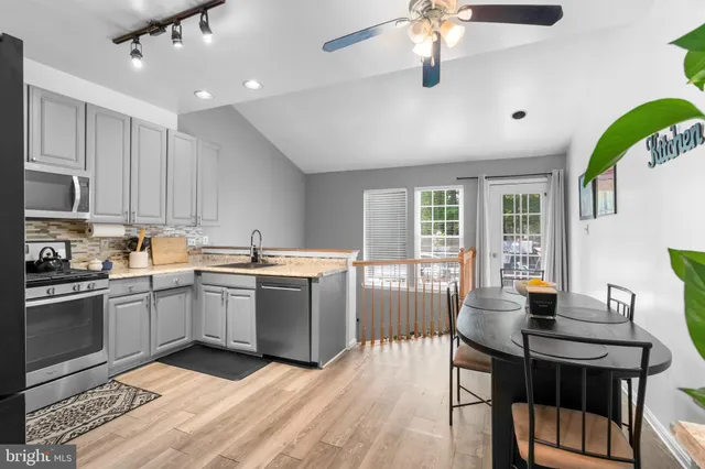 a kitchen with stainless steel appliances granite countertop a stove a sink dishwasher a dining table and chairs with wooden floor