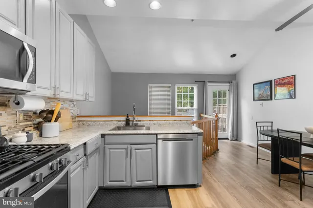 a kitchen with stainless steel appliances a sink dishwasher stove and wooden cabinets