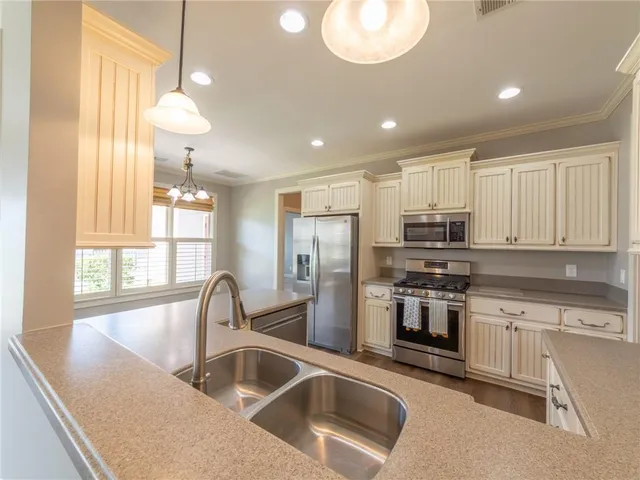a kitchen with stainless steel appliances granite countertop a sink a stove and a refrigerator